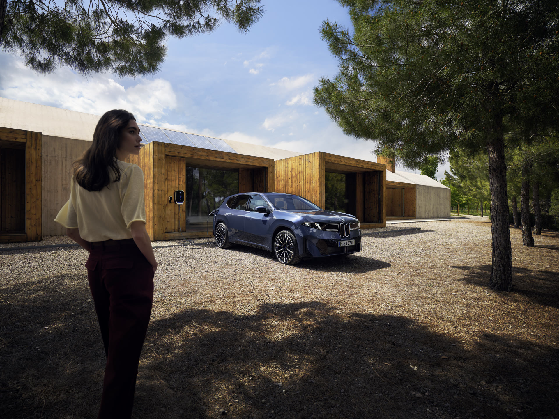 BMW vor Holzhaus bei Tag, Solar-Panels auf dem Dach als CGI integriert